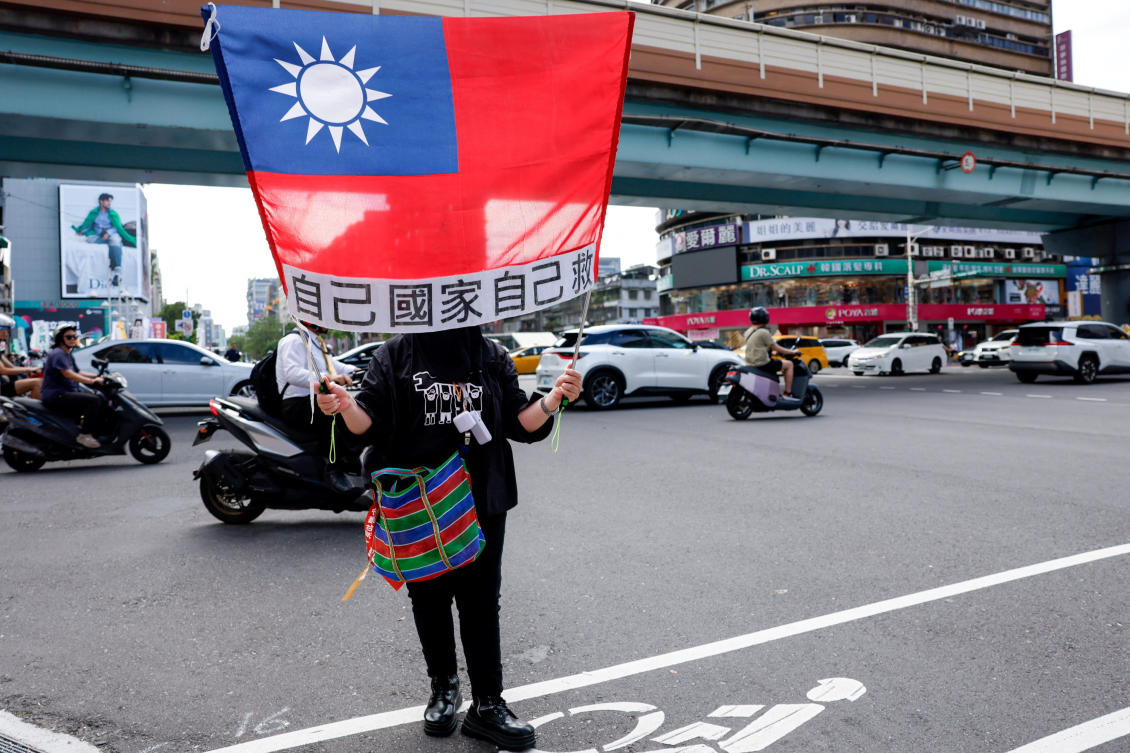 Above, a person holds a Taiwan flag at a rally to support government plans to increase defense spending in Taipei on May 23, 2026. (Reuters)