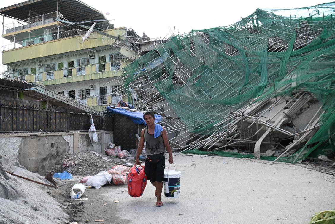 A worker carries belongings retrieved from the collapsed building in Angeles City, Pampanga province, north of Manila on May 25, 2026. (AFP)