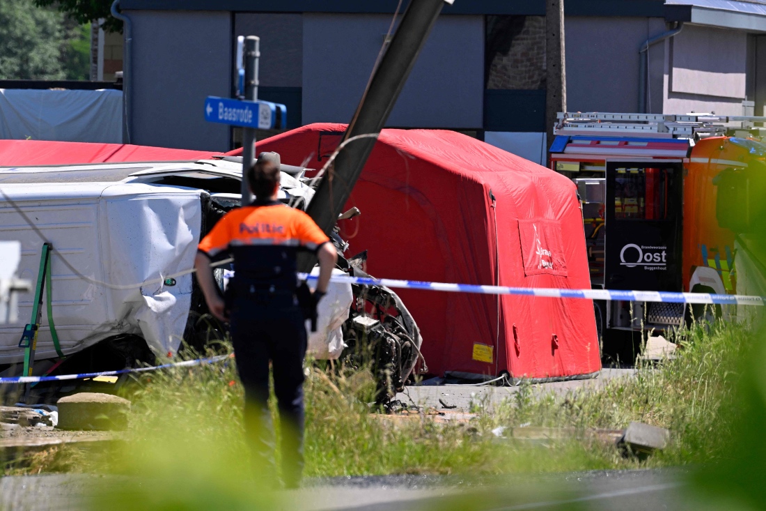 A police officer stands next to a damaged bus at the site of an accident after a train crashed into a school bus, at the railway crossing Vierhuizen in Buggenhout, Belgium. (AFP)