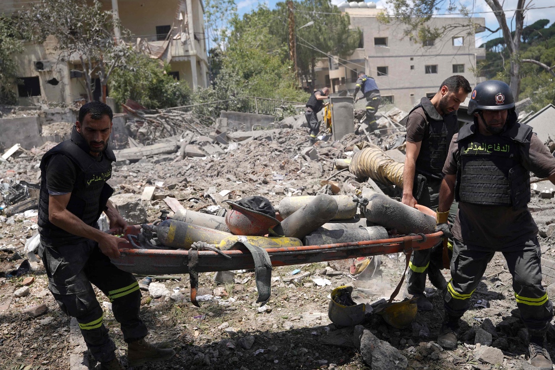 Emergency workers use a stretcher to remove oxygen bottles from under the debris of a civil defense center damaged in an Israeli air strike on the southern Lebanese city of Nabatiyeh. (AFP)