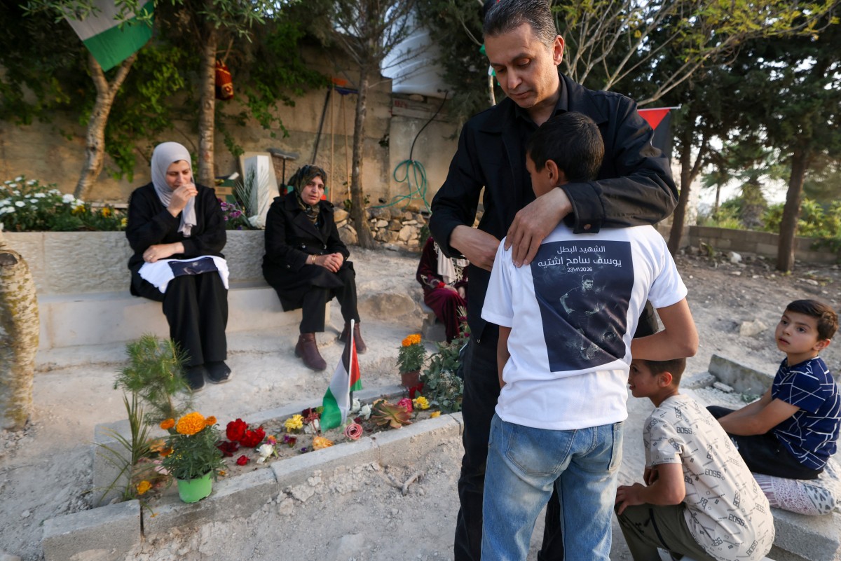 Sameh Shtayyeh, the father of 15-year-old Youssef Sameh Shtayyeh who was killed on April 23, by Israeli soldiers in the city of Nablus, hugs his son as they visit his grave at the cemetery in the village of Till, west of Nablus, in the Israeli-occupied Palestinian West Bank. (AFP)