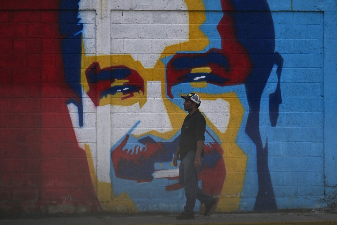 A man walks past a graffiti depicting Venezuelan President Nicolas Maduro in Caracas, Venezuela. (AFP)