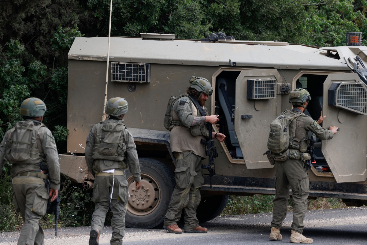 Israeli soldiers react after taking cover near the Israel-Lebanon border following a Hezbollah drone attack that hit the northern border. (AFP)