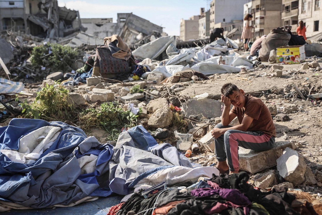 A Palestinian boy sits at the site of an overnight Israeli military strike on structures and tents housing displaced families, killing ten Palestinians, in Gaza City. (AFP)