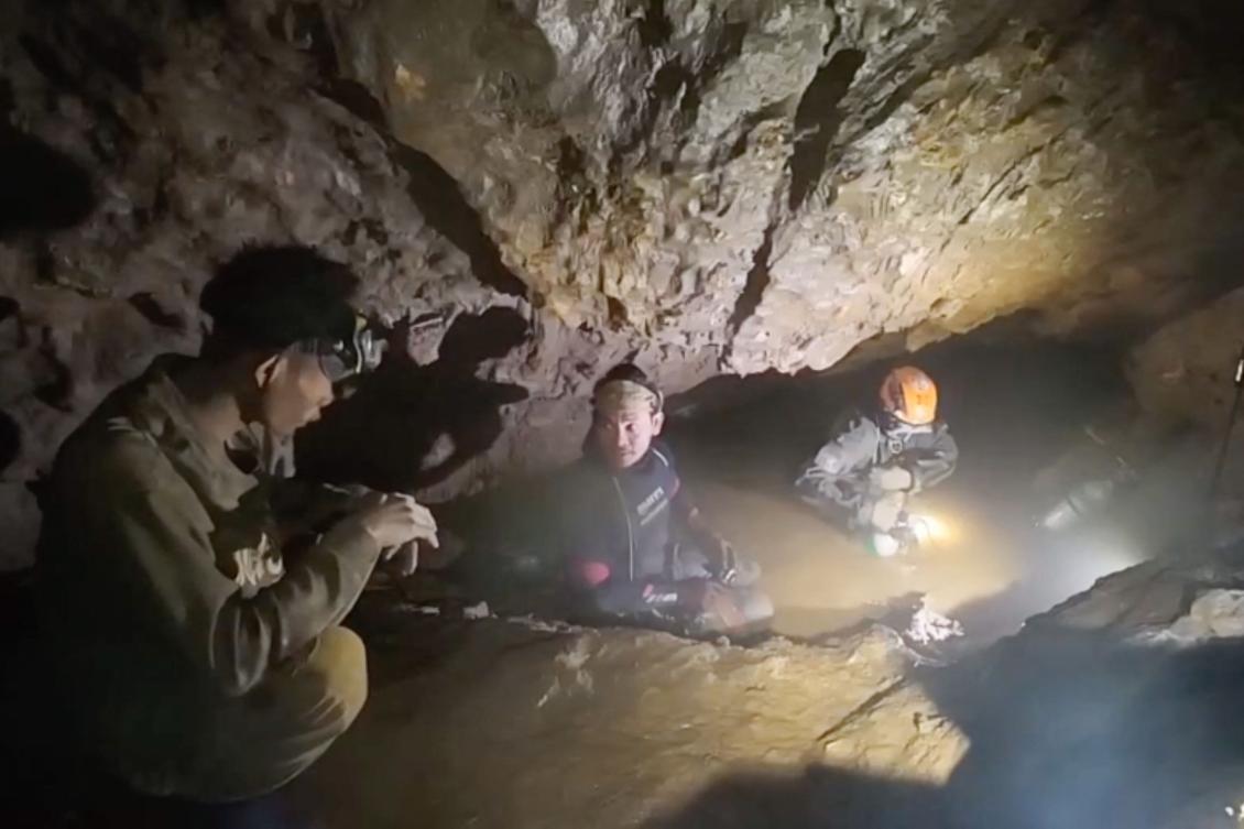 This screengrab made from handout video footage taken on May 29, 2026, and provided by Benz Norrased Palasing of Seascout Diving, shows a rescue team (C, R) about to free one (L) of seven men trapped in a semi-submerged cave in central Xaysomboun province, northeast of the capital Vientiane. (Photo by AFP)