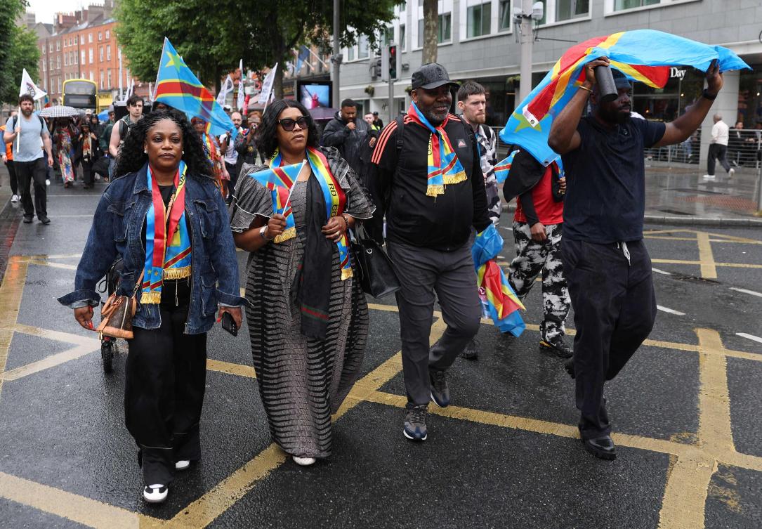 Dublin-based producer and musician Chris Kabs (R) walks with a Congolese flag, down O’Connell Street in central Dublin at the head of a protest to demand justice following the death of Congolese citizen Yves Sakila, after he was violently restrained by shop security guards who suspected him of shoplifting, on May 30, 2026. (AFP)