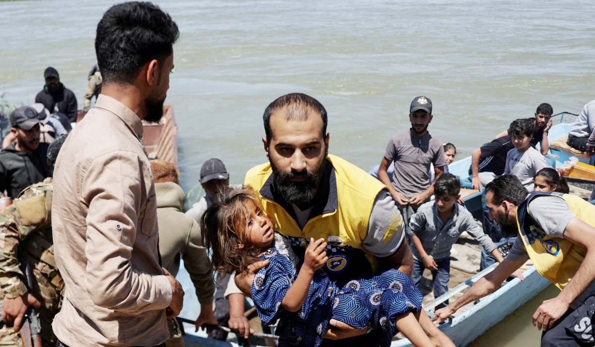 A member of the Syrian Civil Defence, also known as the White Helmets, carries a child after water levels rise due to increased dam releases following heavy rainfall this year, in Deir al-Zor, Syria, May 30, 2026. (REUTERS)
