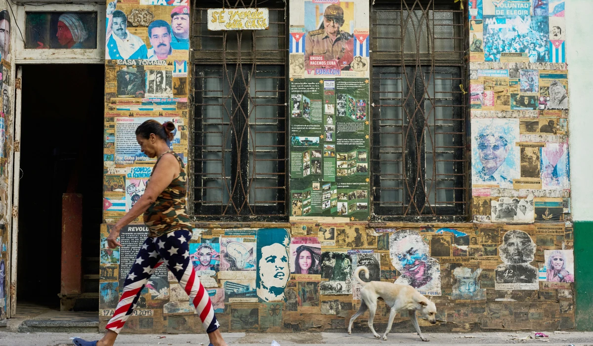 A woman wearing U.S. flag motif pants walks past a building that houses an art installation on the Cuban Revolution, featuring photos of former Cuban President Raul Castro and former Venezuelan President Nicolas Maduro, in Havana, Cuba, Tuesday, May 19, 2026. (AP)