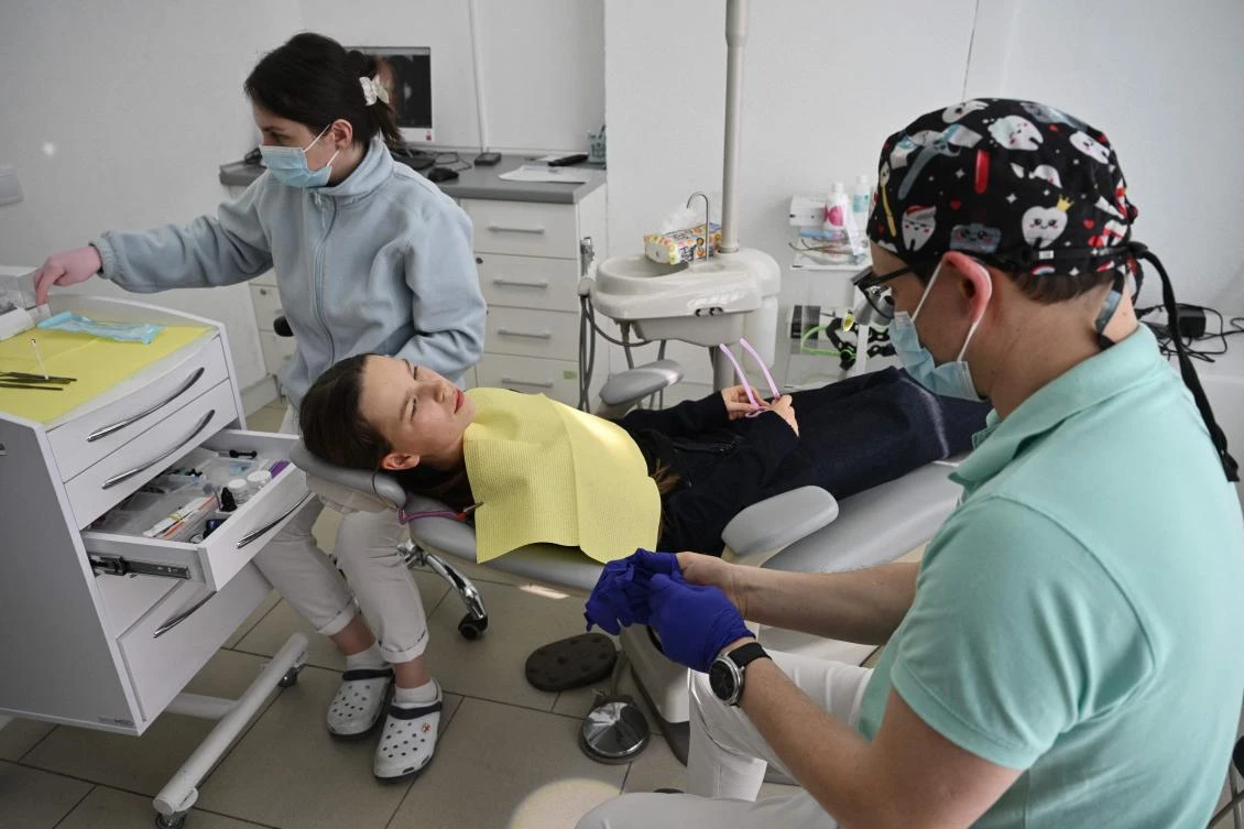 Daryna receives dental care by dentist Oleg Kovnatskyi (R) at a clinic in Kyiv on April 30, 2026. (AFP)
