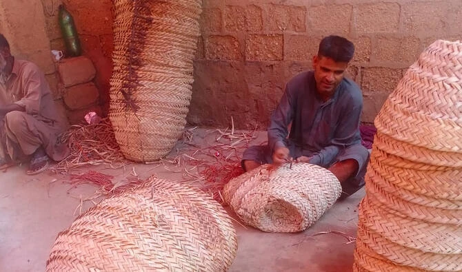 A man weaves a traditional basket from dried reeds and palm leaves in Lyari, Karachi. (AN photo)