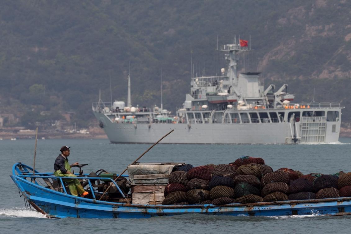 Above, a fishing boat sails past a Chinese warship during a military drill off the Chinese coast near Fuzhou, Fujian Province on April 11, 2023. (Reuters file photo)