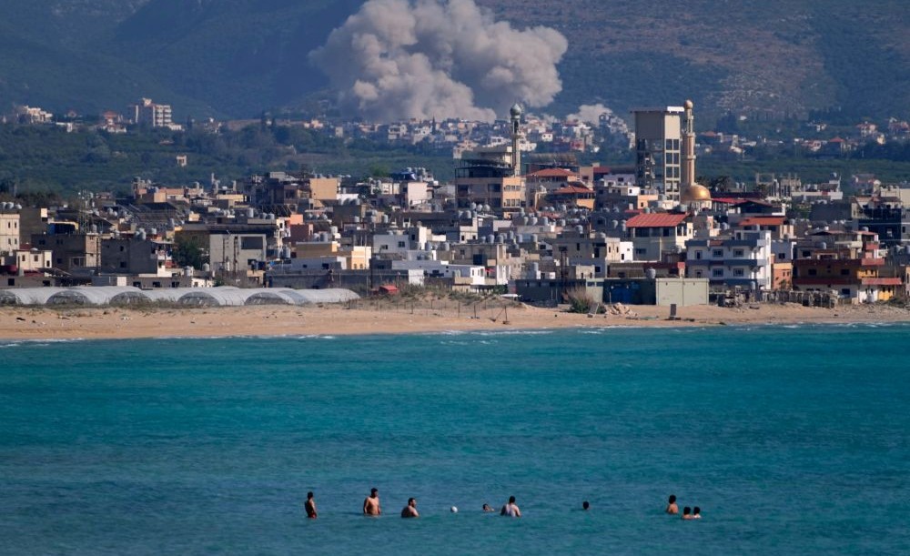 People swim on a public beach as smoke rises from an Israeli airstrike on Qlaileh village, as seen from the southern port city of Tyre, Lebanon, Tuesday, June 2, 2026. (AP Photo)