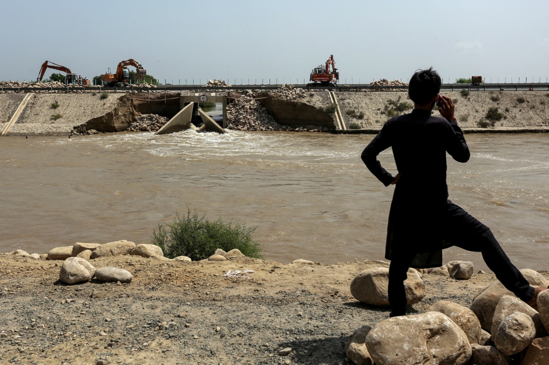 A man watches as local authorities use excavators to fill the damaged section of the motorway with rocks to prevent floodwater from entering at Jalalpur Pirwala, Pakistan. (AFP)