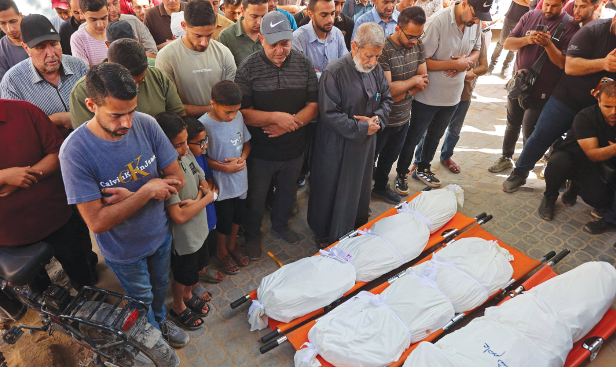 Palestinians pray over the bodies of people killed in Israeli airstrikes in Gaza City on Thursday. Daily violence continues to rock the war-torn enclave. (AFP)
