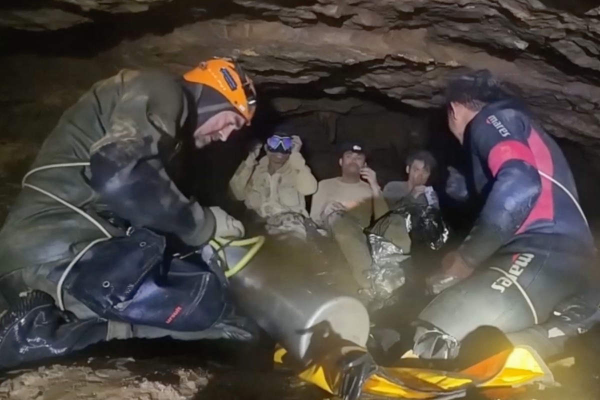 This screen grab made from handout video footage taken on May 30, 2026, and provided by Adisak Wongsoraya, shows two men (centre L and centre R, with headlamp) being hugged after they were rescued from a semi-submerged cave in Laos' central Xaysomboun province, northeast of the capital Vientiane. (AFP)