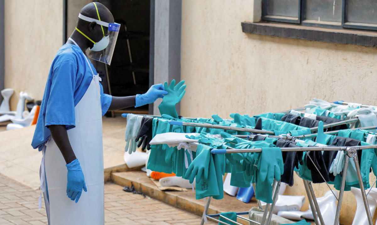 A Ugandan worker collects a rubber glove from the airing line during a visit by the Director-General of the World Health Organization (WHO) Tedros Adhanom Ghebreyesus at the Mulago National Referral Hospital Isolation Unit. (Reuters)