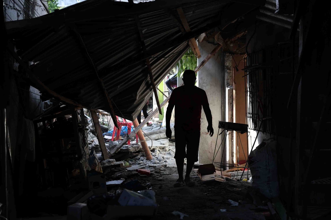 A resident walks past debris from damaged houses following an earthquake in General Santos, Philippines. (AP)