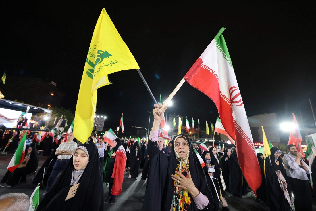 Pro-government Iranian demonstrators wave flags of Iran and Lebanon's Hezbollah movement after Israeli strikes on Beirut's southern suburbs in Tehran, Iran. (AFP)