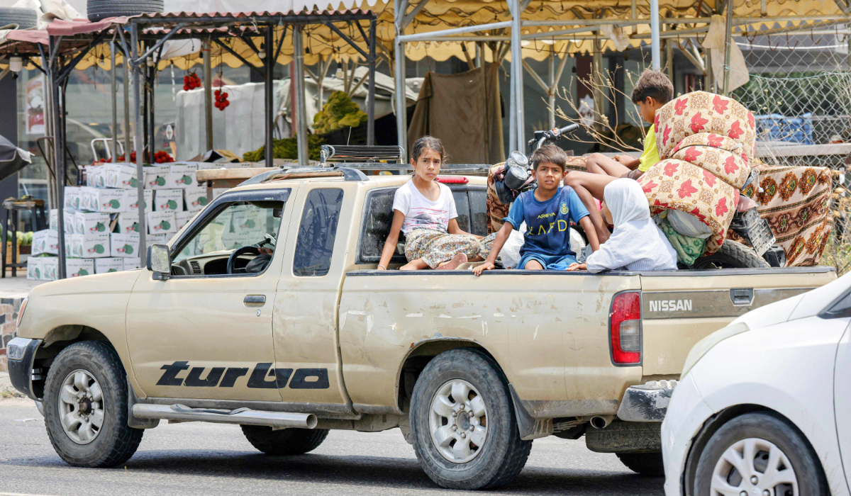 Children sit in the bed of a pickup truck waiting in traffic, as people fleeing from Tyre in southern Lebanon after Israel's evacuation warning seek refuge in more northerly Sidon, on June 9, 2026. (AFP)