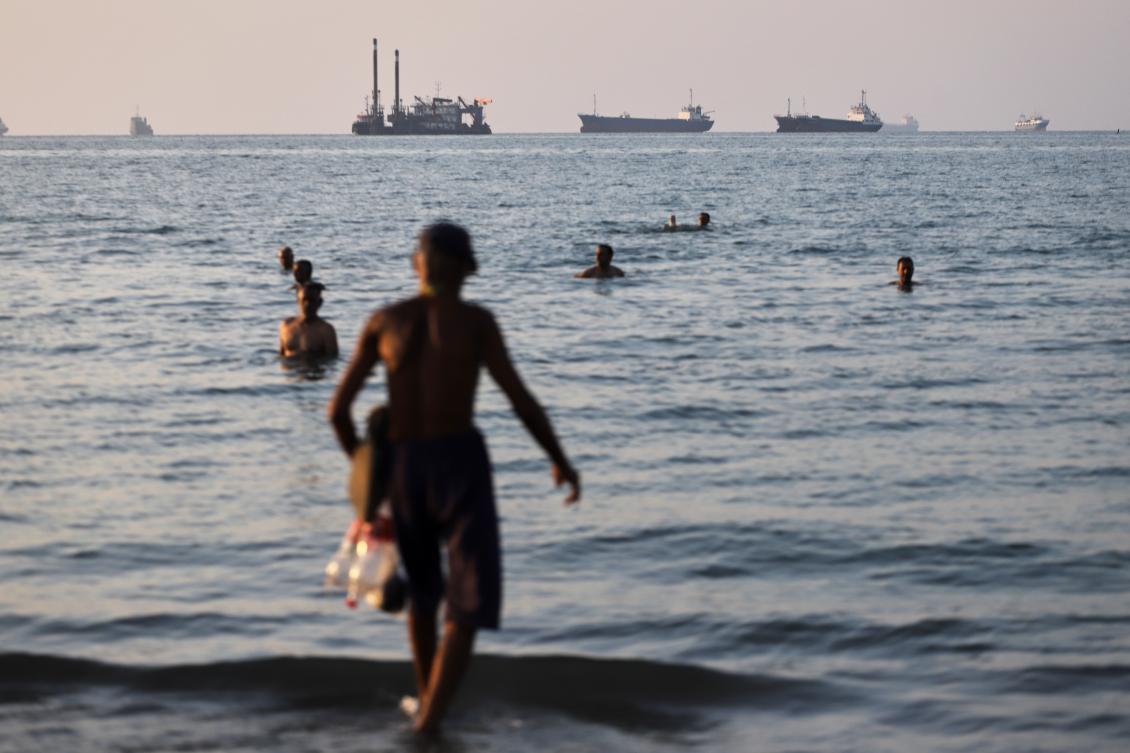 Resident swim as cargo and commercial vessels are anchored in the Strait of Hormuz off Bandar Abbas, Iran, Monday, June 8, 2026. (Amirhosein Khorgooi/ISNA via AP)