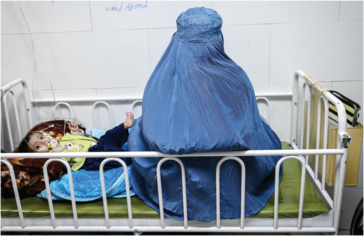 This photograph taken on January 8, 2026 shows an Afghan woman sitting next to her malnourished child inside the Medecins Sans Frontieres (MSF) therapeutic nutrition centre at a hospital in Herat. (AFP)