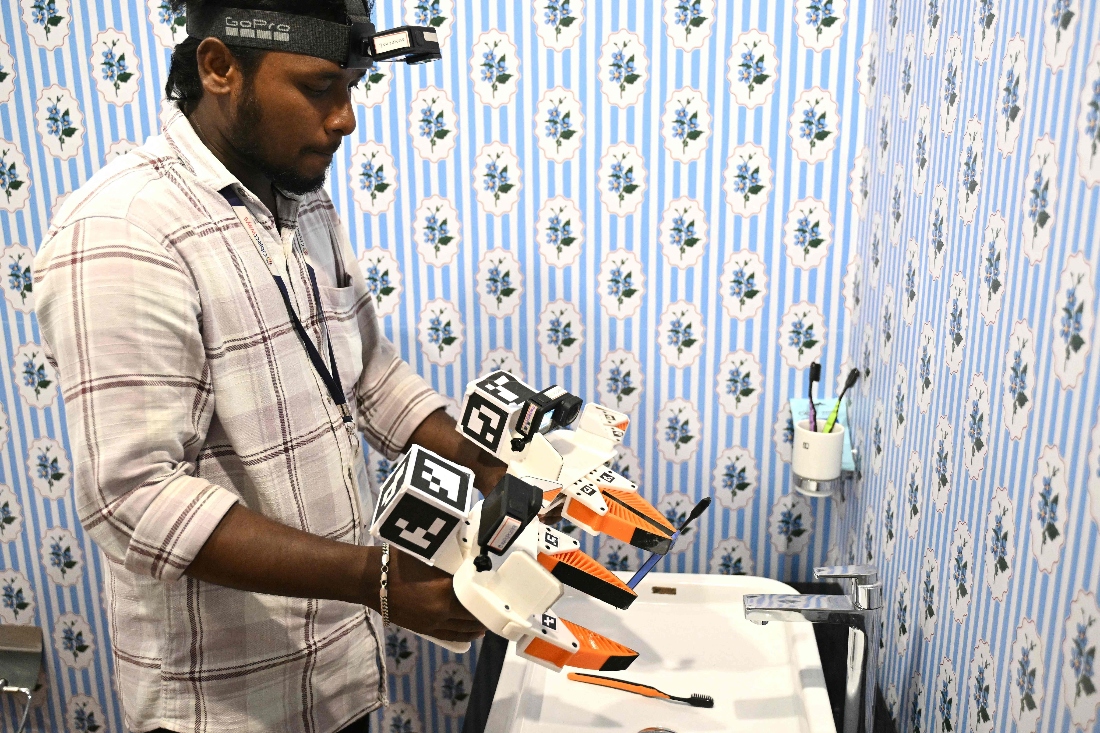 A worker wearing a GoPro camera on his head recording actions through motion capture inside a model bathroom at AI data company Objectways' office in Tamil Nadu's Karur district, India. (AFP)