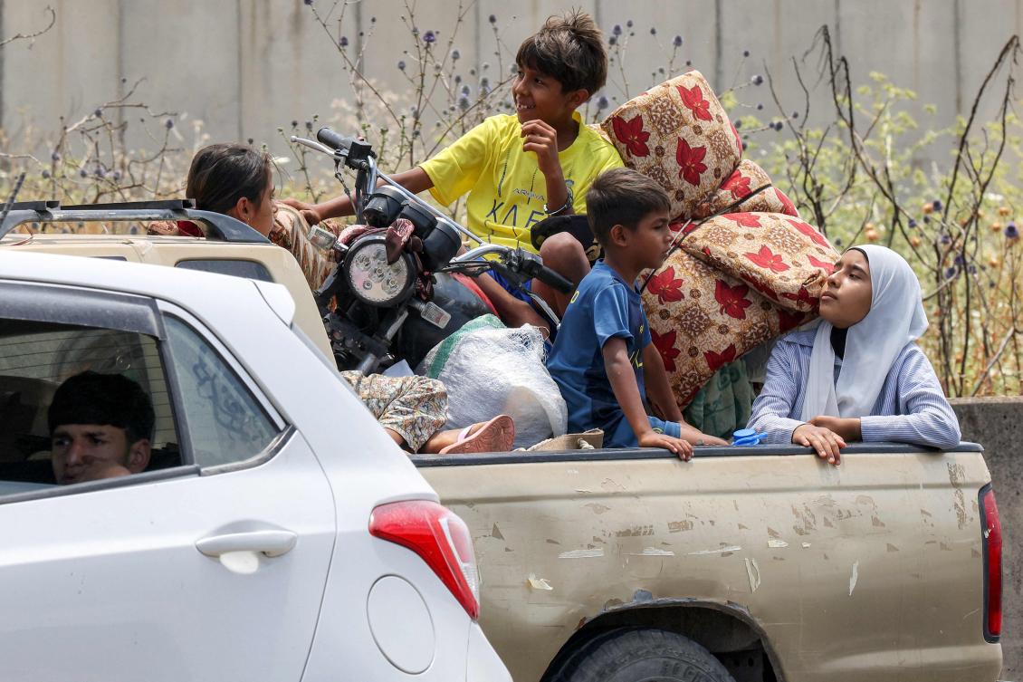 Children sit in the bed of a pickup truck waiting in traffic, as people fleeing from Tyre in southern Lebanon after Israel’s evacuation warning seek refuge in more northerly Sidon, on June 9, 2026. (AFP)