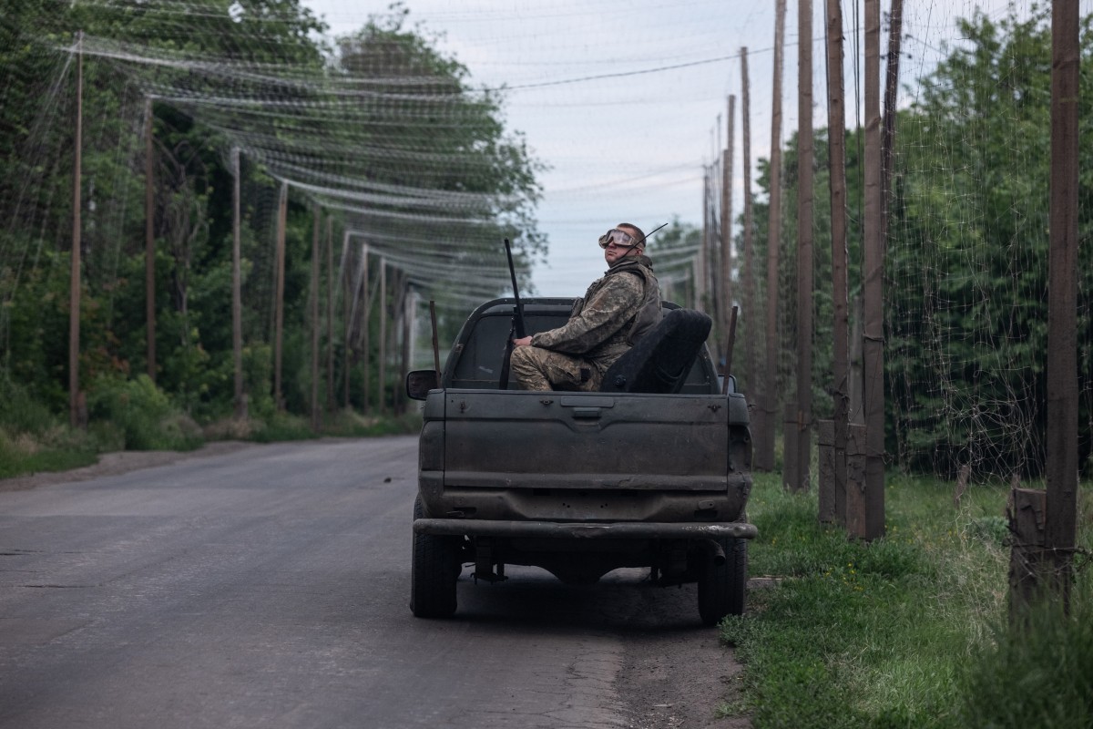 A Ukrainian soldier sits in the back of a car parked on the side of a road covered with a net to protect vehicles from drone attacks at an undisclosed location. (AFP)
