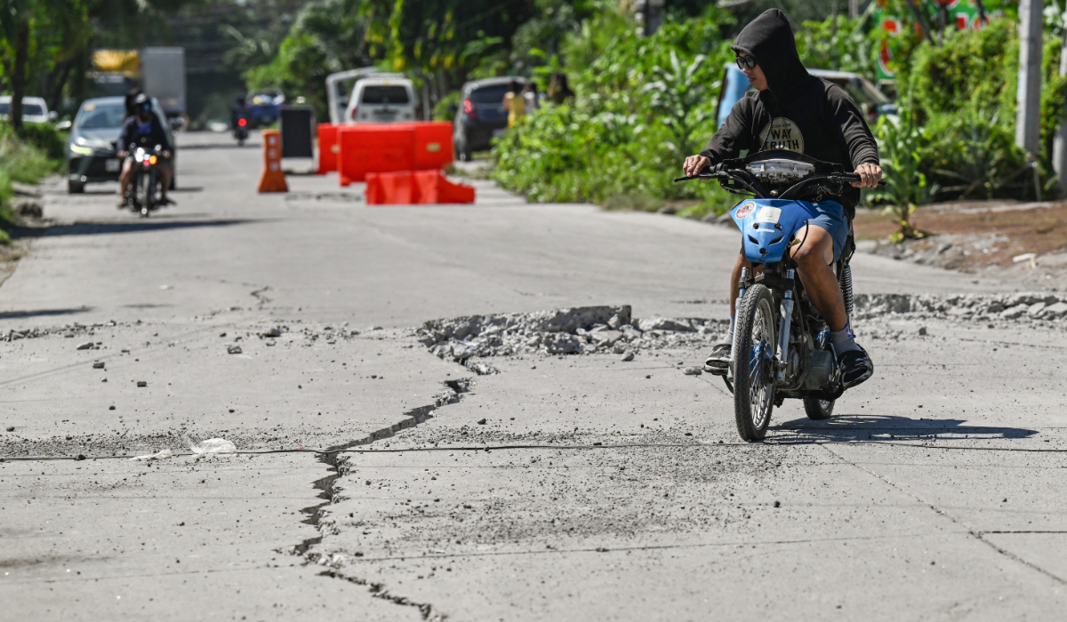 A man rides along a damaged road after a 7.8 magnitude earthquake in General Santos City on June 9, 2026. (AFP)