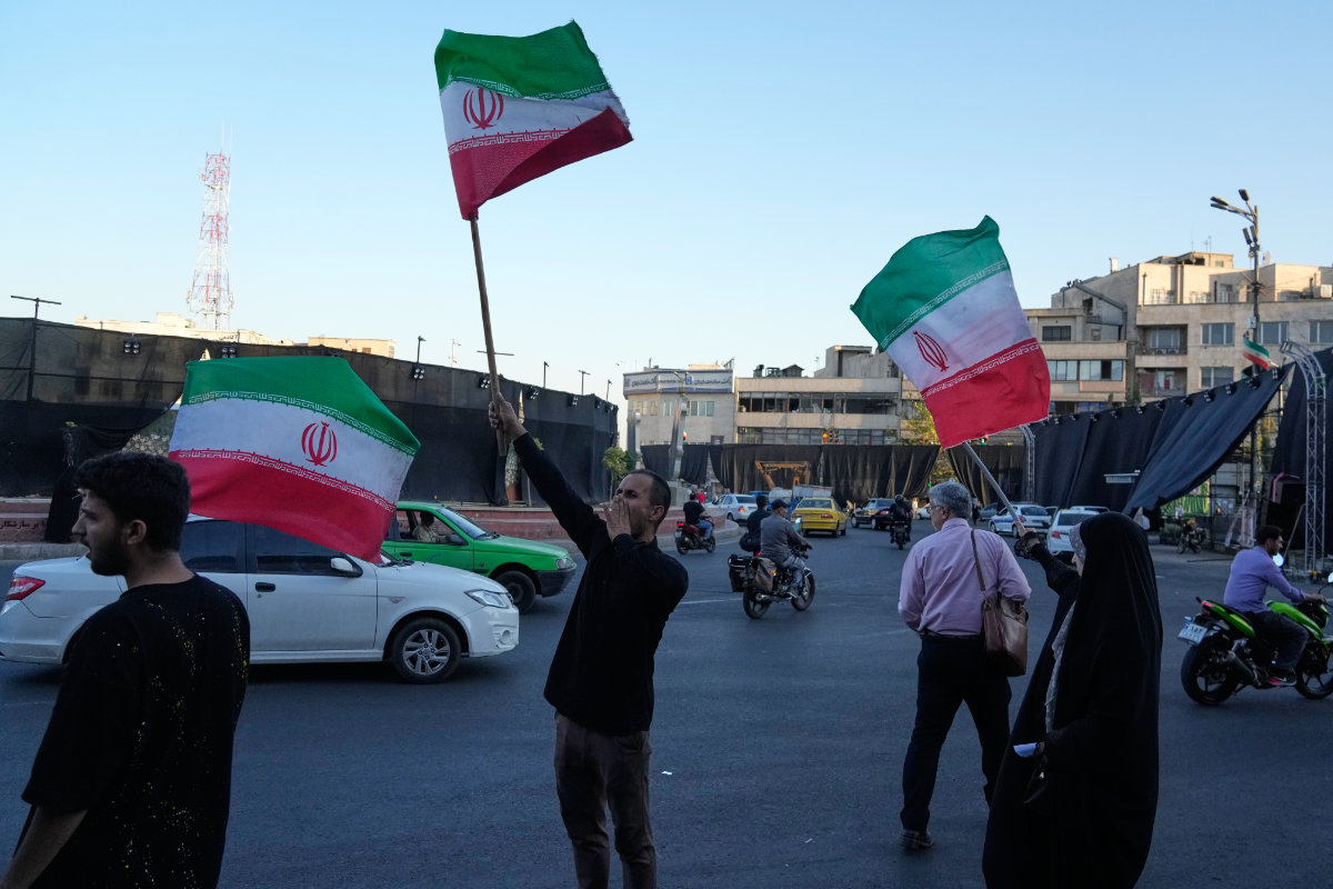 Demonstrators wave Iranian flags as they chant slogans against Iran and US talks at the Islamic Revolution square in Tehran on June 14, 2026. (AP Photo/Vahid Salemi)