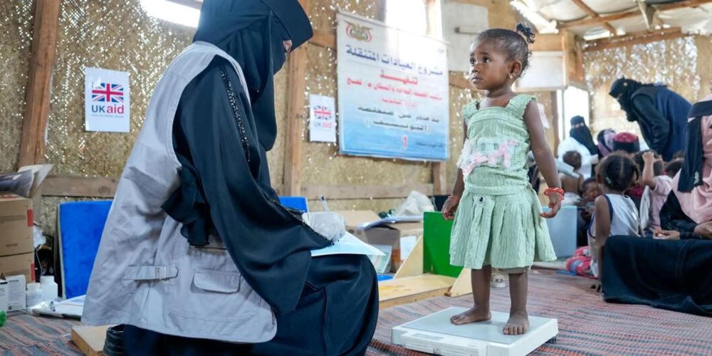 An 18-month-old girl suffering from malnutrition is weighed at a displaced persons (DP) camp in Lahj, Yemen. (UNICEF)