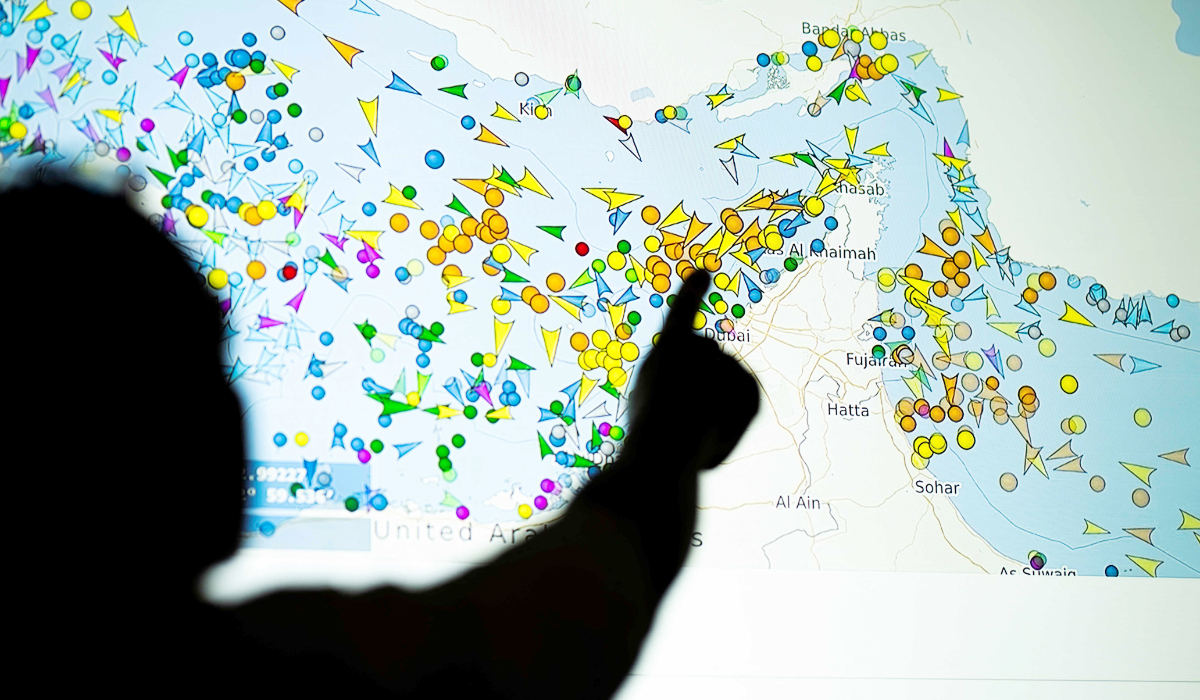 A photo illustration taken in Nicosia on May 4, 2026, shows a person in front of a large screen displaying vessel movements in the Strait of Hormuz on a ship-tracking website. (AFP)