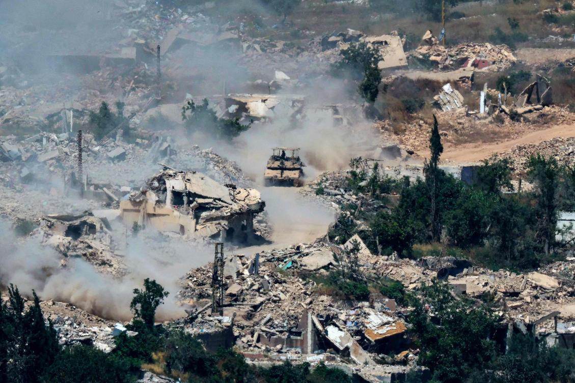 Above, Israeli Merkava tanks drive along a road past destroyed buildings in southern Lebanon on June 17, 2026. (AFP)