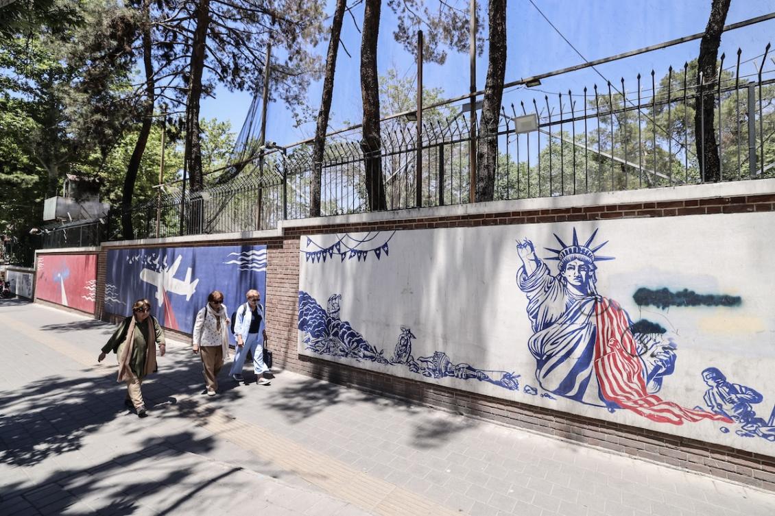 Iranian women walk past anti-US murals outside the former US embassy in Tehran on June 15, 2026. (FILE/AFP)