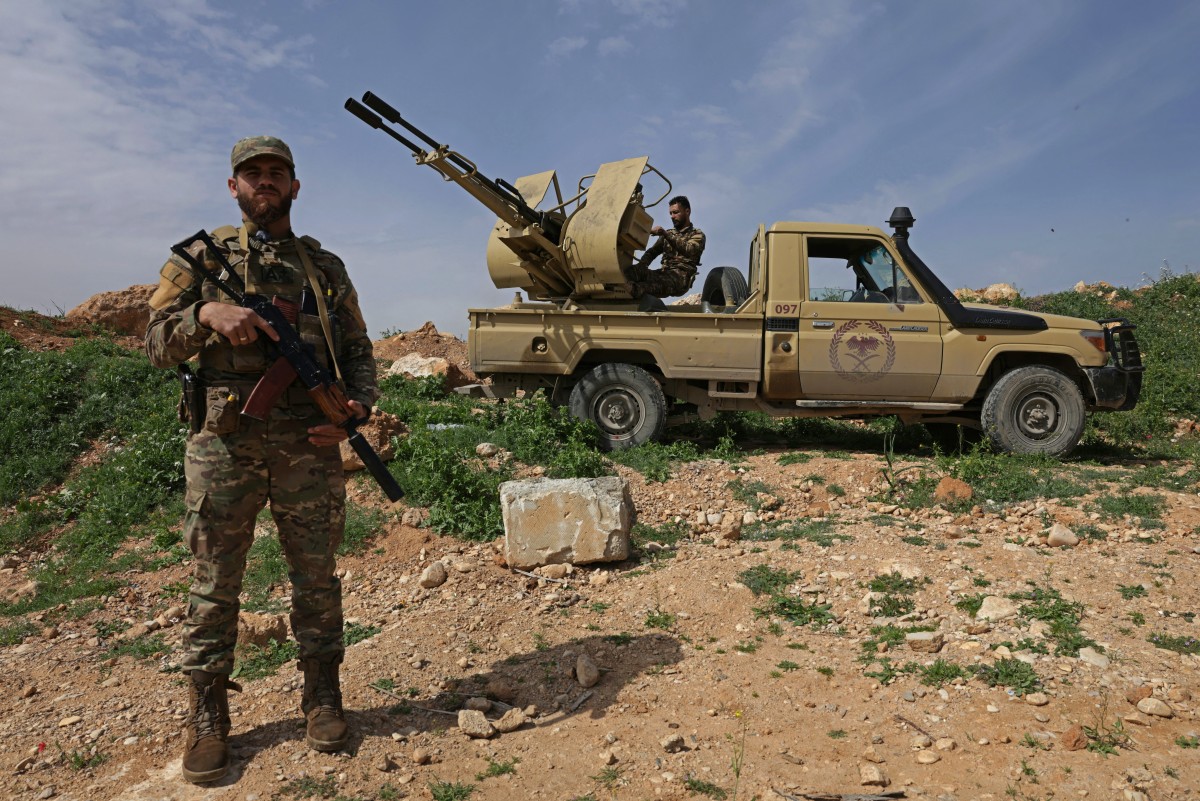 A Syrian army soldier stands guard next to an armoured vehicle positioned along the Syrian–Lebanese border. (AFP)