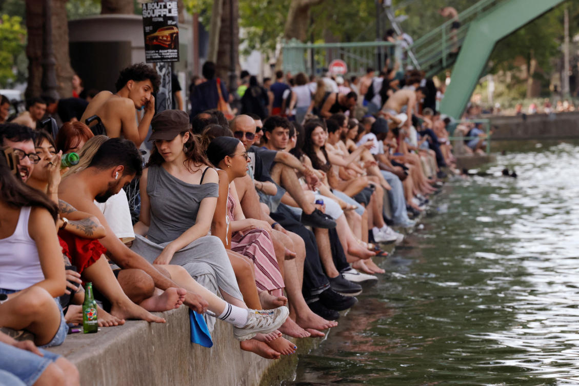 People sit along the Canal Saint-Martin to find some relief from the heat as public swimming having been allowed earlier on part of it due to rising of temperatures, in Paris as a heatwave hits a large of France, Jun. 18, 2026. (Reuters)