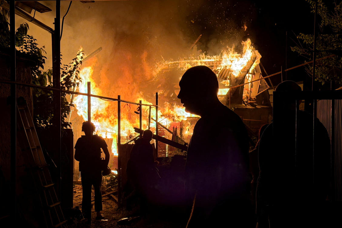 Residents look at a private house that burns after an overnight Russian drone strike, amid Russia's attack on Ukraine, in Zaporizhzhia, Ukraine June 22, 2026. Picture taken with a mobile phone. (Reuters)