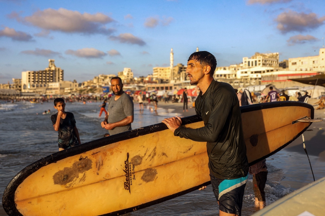 Palestinian surfer Hussein Abu Assi, 23, takes his surfboard out into the Mediterranean sea off a beach in Gaza City. (AFP)