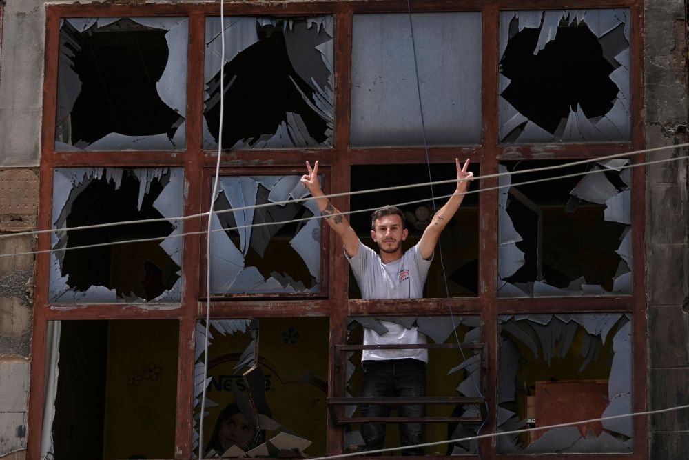 A man flashes the victory sign through the shattered window of a damaged apartment following a ceasefire between Israel and Hezbollah, Nabatiyeh, southern Lebanon, June 22, 2026. (AP Photo)