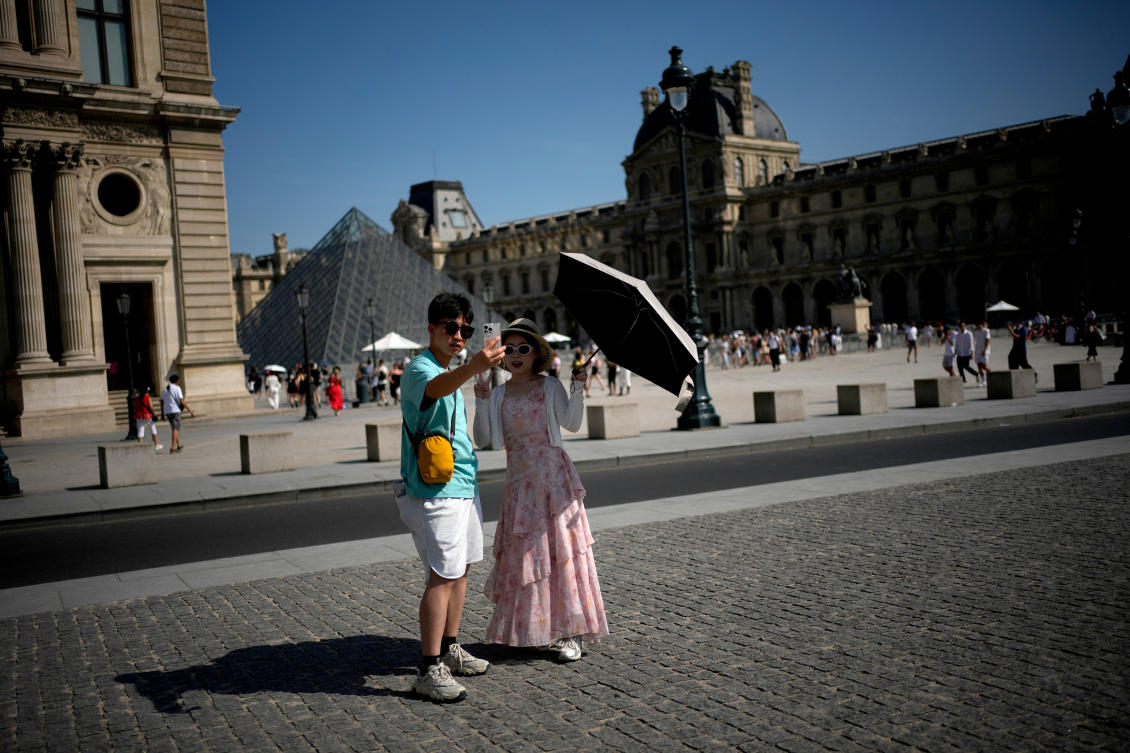 Above, tourists with an umbrella take a photo in Paris. The French capital broke another June record with 37.7°C recorded Monday afternoon. (AP)