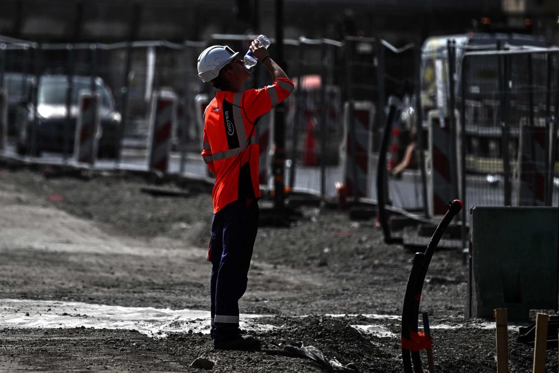 A worker drinks water from a plastic bottle at a construction site in Bordeaux on June 22, 2026, as France experiences a ferocious heatwave. (AFP)
