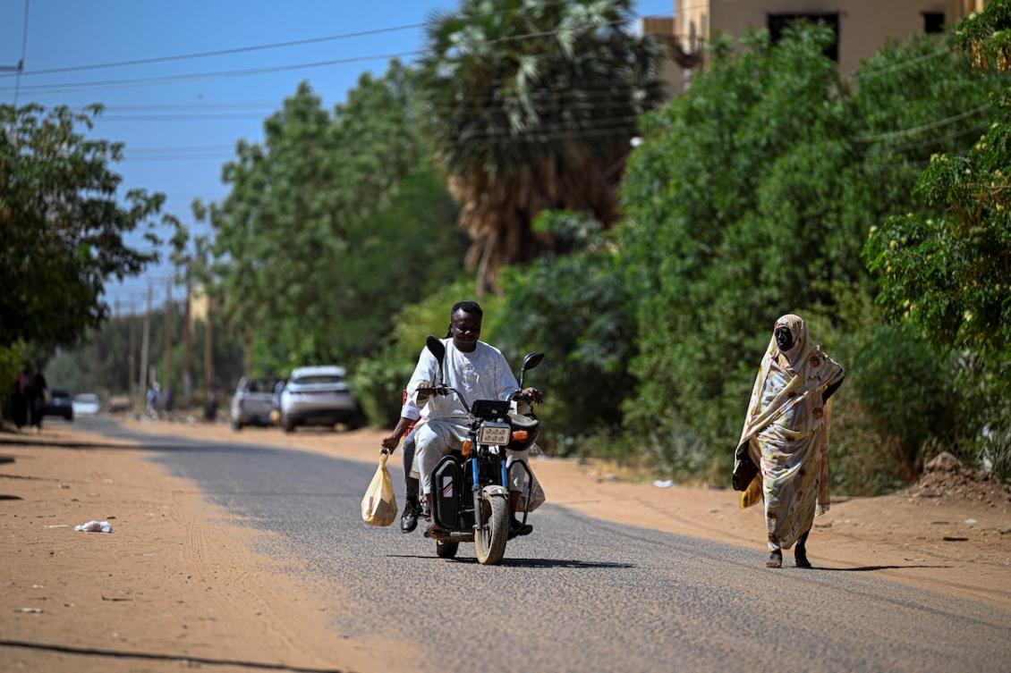This photo taken on April 18, 2026 shows Sudanese Ali Gebbai, a volunteer responsible for delivering free medicine to patients in their homes, riding a bike with his colleague as they carry bags filled with medicine in the capital Khartoum, amid the conflict between the Sudanese army and the paramilitary RSF, who have been locked in a war, since April 2023, that has killed tens of thousands and displaced nearly 12 million people. (FILE/AFP)