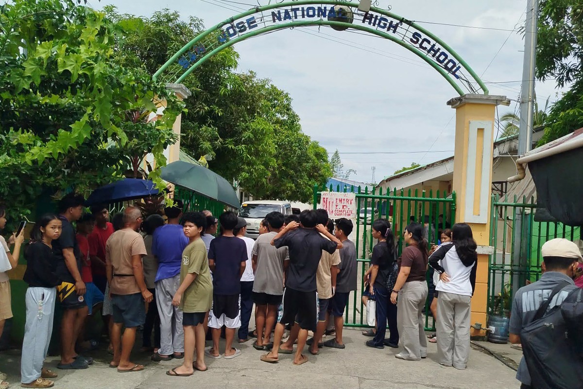 Students and their parents wait for permission from school authorities to enter the school compound at the gate of San Jose High School in Tacloban City, Leyte province on June 23, 2026, a day after a shooting incident. (AFP)
