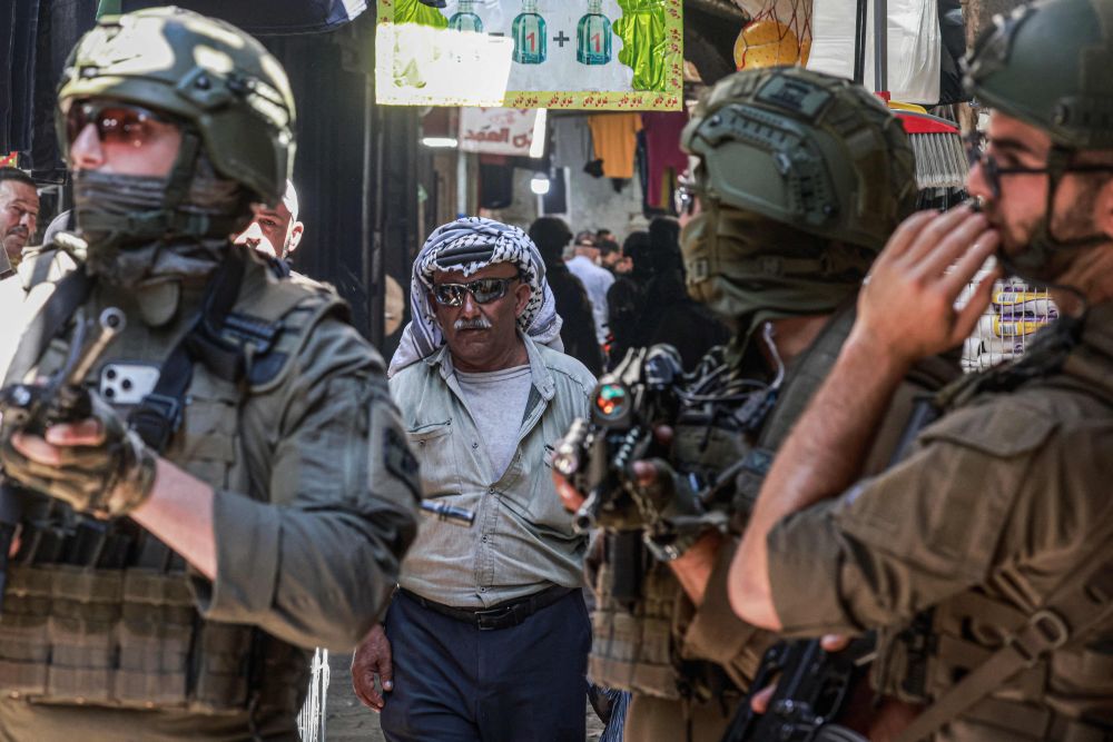 A Palestinian man walks past Israeli soldiers in Nablus, Israeli-occupied West Bank, June 23, 2026. (AFP)