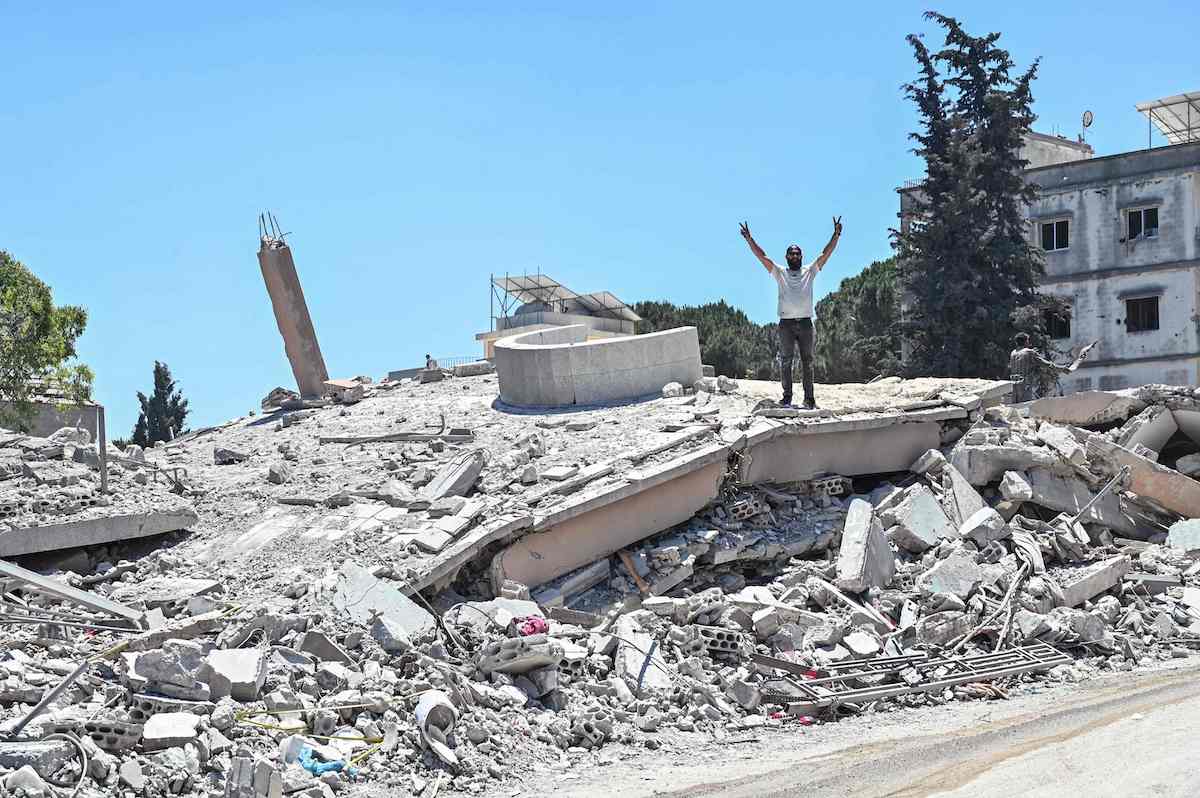A resident stands on the roof of a collapsed home, destroyed in Israeli military strikes, in the southern Lebanese village of Srifa on Wednesday. (AFP)