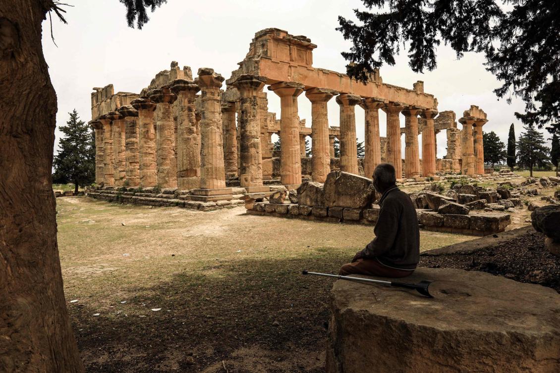 A man sits in the shade in front of the Temple of Zeus at the archaeological site of Cyrene, near the town of Shahat on Libya’s northeastern Mediterranean coast, on May 18, 2026. (AFP)