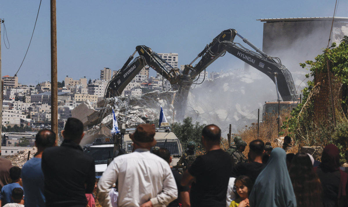 Bulldozers guarded by Israeli soldiers demolish the home and shops belonging to Palestinian families in the village of Qilqes. (AFP)