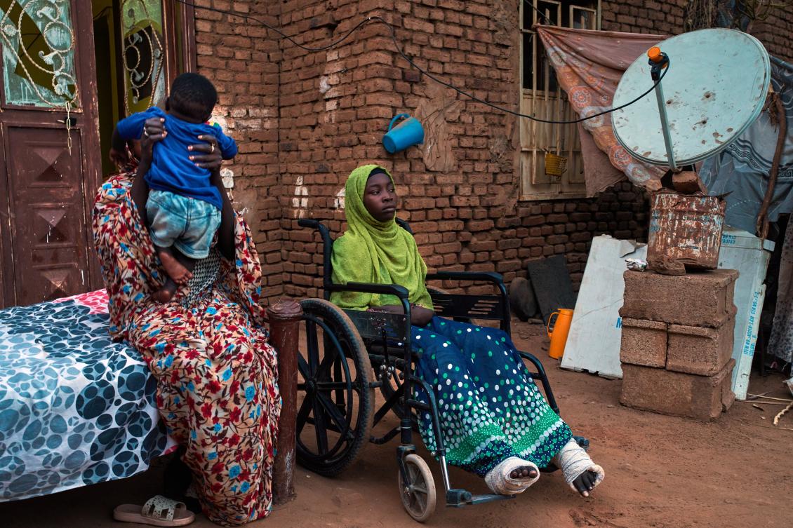Noon Madani, 18, center, who was injured in a shelling attack, sits in a wheelchair on the patio of her family home in Khartoum, Apr. 27, 2026. (AP)