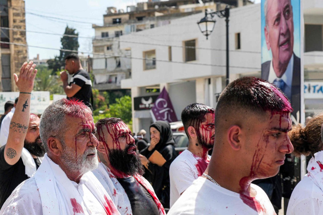Shia Muslim devotees who have cut their scalps during a religious mourning event at the peak of Ashura, walk in a procession past buildings destroyed by Israeli bombardment in Nabatieh in southern Lebanon on June 26, 2026. In his Ashura speech, Hezbollah's leader said on June 26 that Israel has "no option" but to withdraw from Lebanese areas it occupies. (AFP)