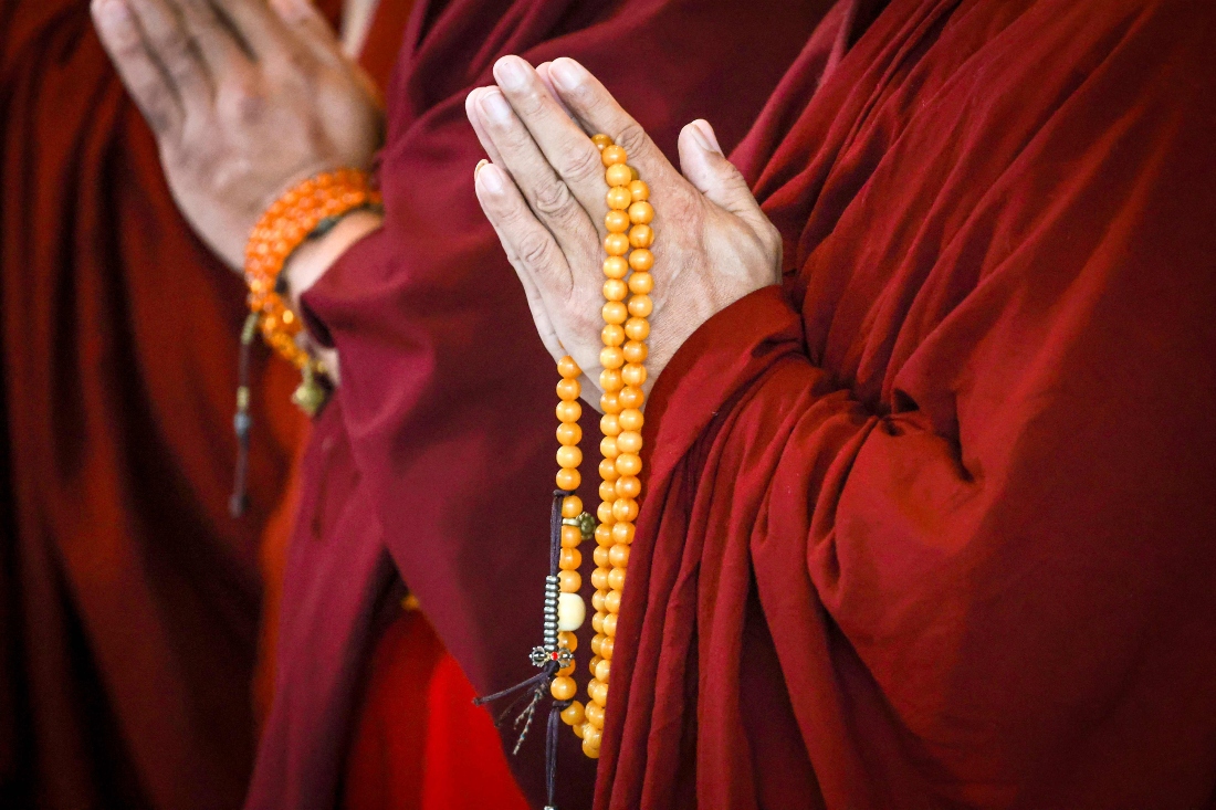 A monk holds prayer beads as he prays with Tibetan lama Kundeling Tatsak Rinpoche. (AFP)